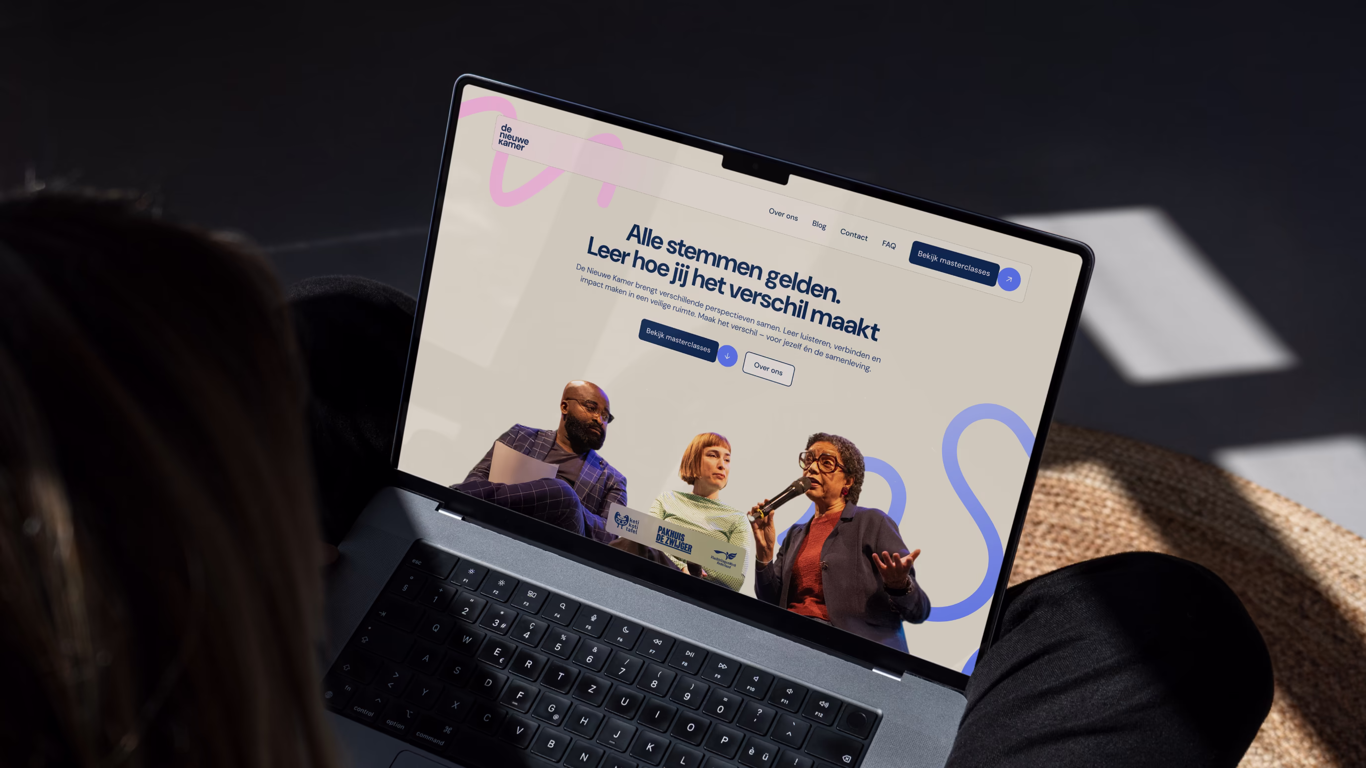 Person viewing a laptop screen showing the website of De Nieuwe Kamer.