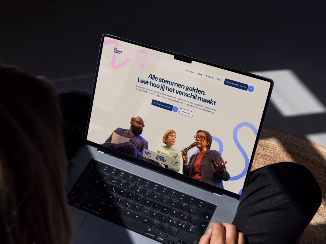 Person viewing a laptop screen showing the website of De Nieuwe Kamer.